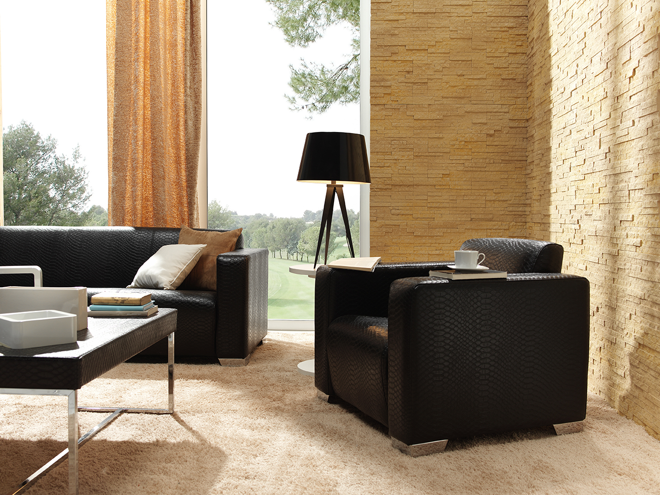 black sofa and chair with tan panel stone wall