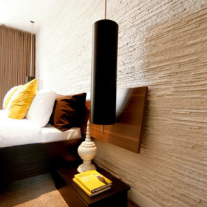 hotel room bed against a white premier textured wall