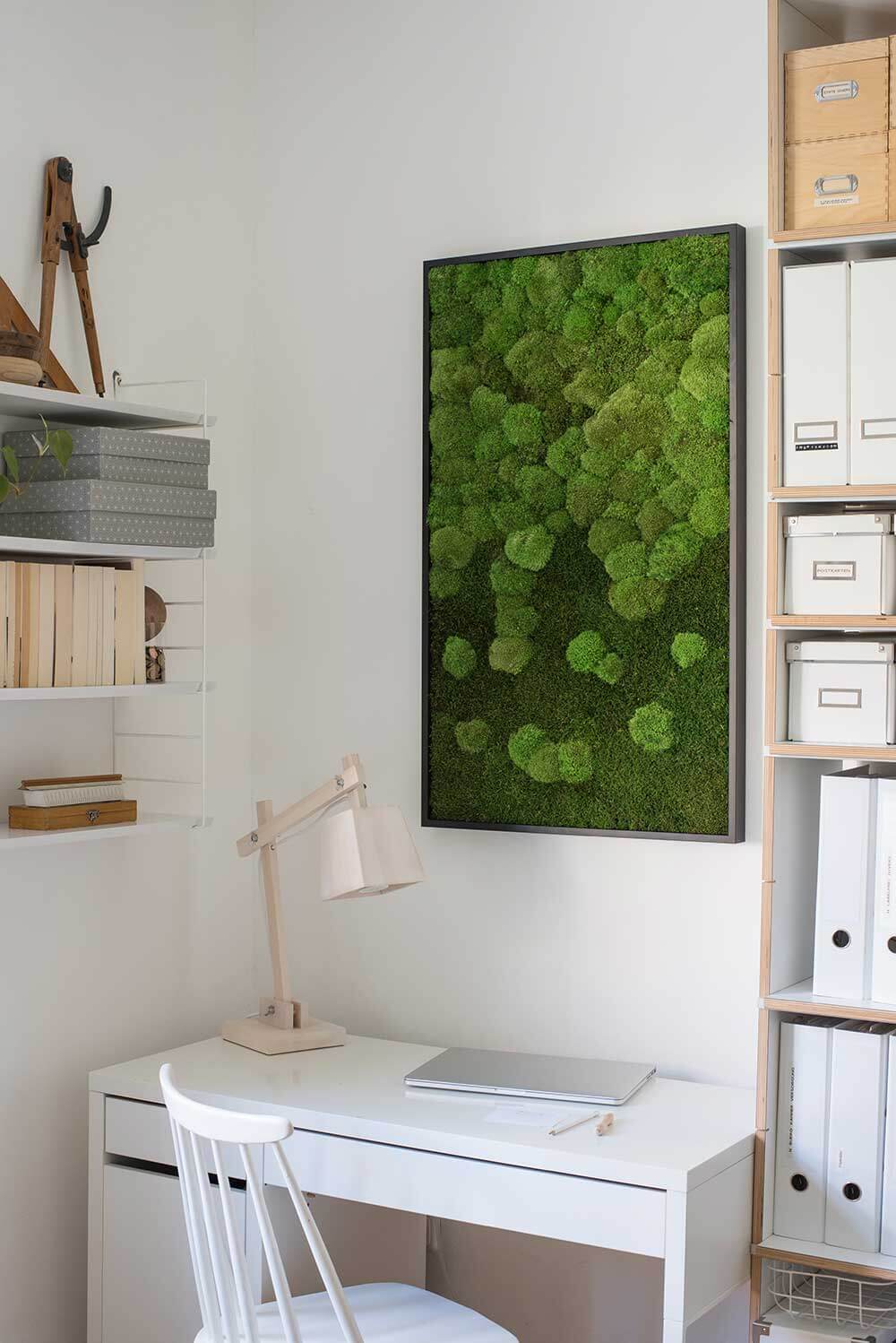 white desk and chair against white wall with a rectangle frame of moss on it