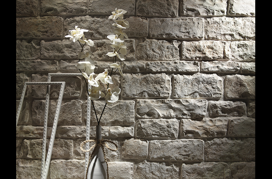 stone wall tan behind frames and flowers in a vase