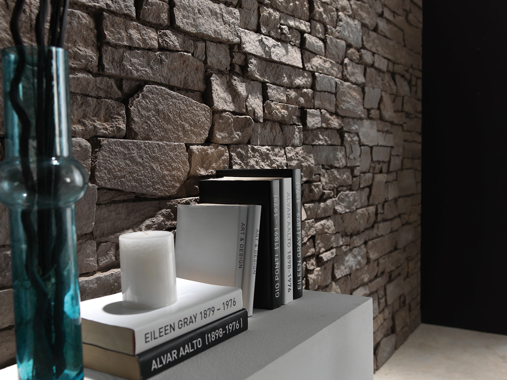 rugged brown stone wall behind white table with books on it