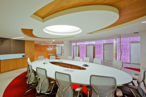 conference room with white table and chairs with wooden circle design on ceiling and wooden cabinets