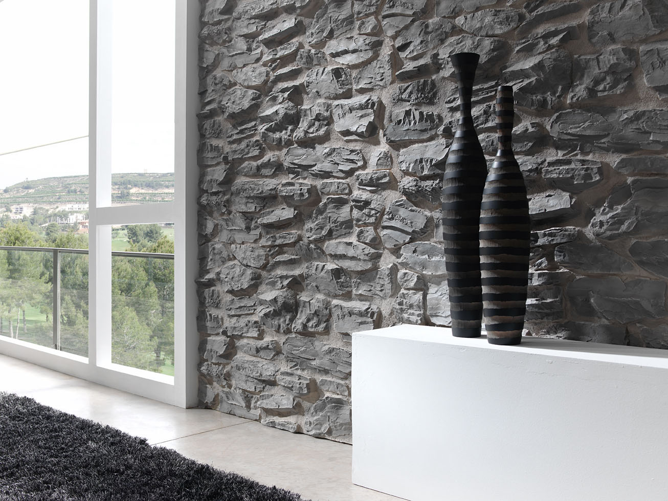 stone textured wall next to window whit white table in front of it with black bottles on the table