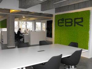 room with table and chairs and one wall covered in moss, in darker moss are the letters e, b, and r