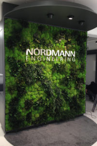 wall covered in greenery and moss with a metal sign